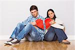 Young couple sitting on floor with broken heart at home