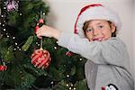 Child hanging up tree decorations on the christmas tree