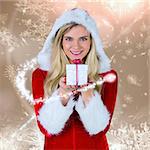 Pretty girl in santa outfit holding gift against cream snow flake pattern design