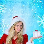 Pretty girl in santa outfit holding gift against blue snow flake pattern design