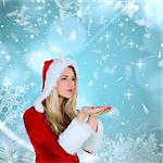 Pretty girl in santa outfit blowing against blue snow flake pattern design