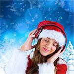 Sexy santa girl listening to music against snowy landscape with fir trees
