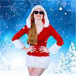 Cool santa girl wearing sunglasses against snowy landscape with fir trees