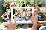 Hands holding tablet pc against happy family playing together in a picnic