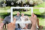 Hands holding tablet pc against senior couple sitting on a bench