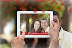 Hands holding tablet pc against couple sitting in the garden