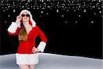 Cool santa girl wearing sunglasses against snowy landscape under night sky