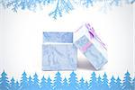 Frost and fir trees in blue against blue gift box with purple ribbon leaning against another