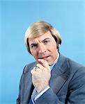 1960s 1970s PORTRAIT OF BUSINESSMAN IN SUIT AND TIE WITH QUIZZICAL EXPRESSION LOOKING AT CAMERA HAND NEAR MOUTH