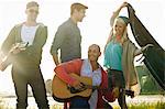 Four adult friends with acoustic guitar and picnic blanket on Bournemouth beach, Dorset, UK