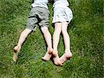 Overhead view of brother and sisters legs as they lay on grass