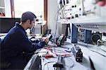 Male electrician repairing electronic equipment in workshop