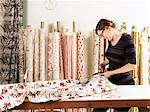 Woman cutting fabric on work table in hand-printed textile workshop