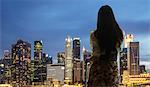 Young woman with suitcase looking at city skyline