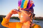 Close up of girl dressed as native american in feather headdress with hand shading eyes