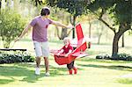 Father and son running with toy airplane in park