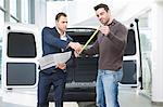 Customer and salesman checking van measurements in car dealership