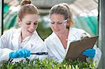 Two female scientists monitoring plant samples and recording data