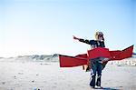 Boy standing with toy airplane and pointing on beach