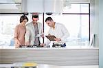 Mid adult couple and salesman looking at hob in kitchen showroom