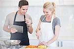 Couple chopping and tasting sliced vegetables in kitchen