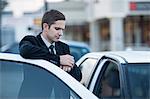 Mid adult businessman looking at watch in city traffic jam