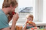 Father and toddler son eating breakfast at kitchen table