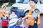 Paramedics wheeling patient on stretcher in hospital parking lot