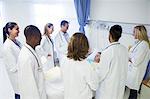 Doctor and residents examining patient in hospital room