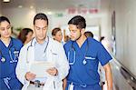 Doctor and nurses reading medical chart in hospital hallway