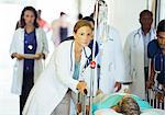 Doctors and nurses wheeling patient in hospital hallway