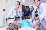 Doctors wheeling patient in hospital hallway