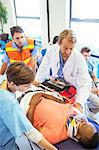 Doctor, nurse and paramedic wheeling patient in hospital