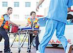 Paramedics wheeling patient in hospital parking lot