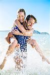 Woman riding piggy back on boyfriend in water