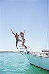 Couple jumping off boat into water