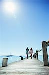 Couple holding hands walking along wooden dock