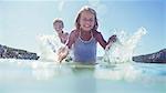 Young girl and brother splashing in water