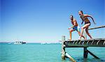 Couple jumping off wooden dock together