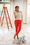 Woman holding paintbrush near paint cans