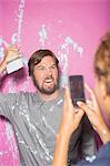 Woman taking picture with cell phone of man with paintbrush