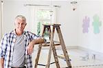 Older man smiling near ladder in livingroom