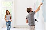 Man painting wall with girlfriend observing