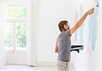 Man painting wall in living space