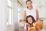 Mother and daughter smiling while clutching teddy bear