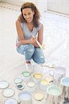 Woman squatting with paintbrush near paint cans