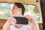 Woman in car backseat taking picture with cell phone