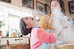 Mother and daughter playing with flour in the kitchen