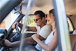 Couple riding in car on sunny day