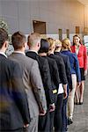 Rear view of businesswoman and business team standing in a row